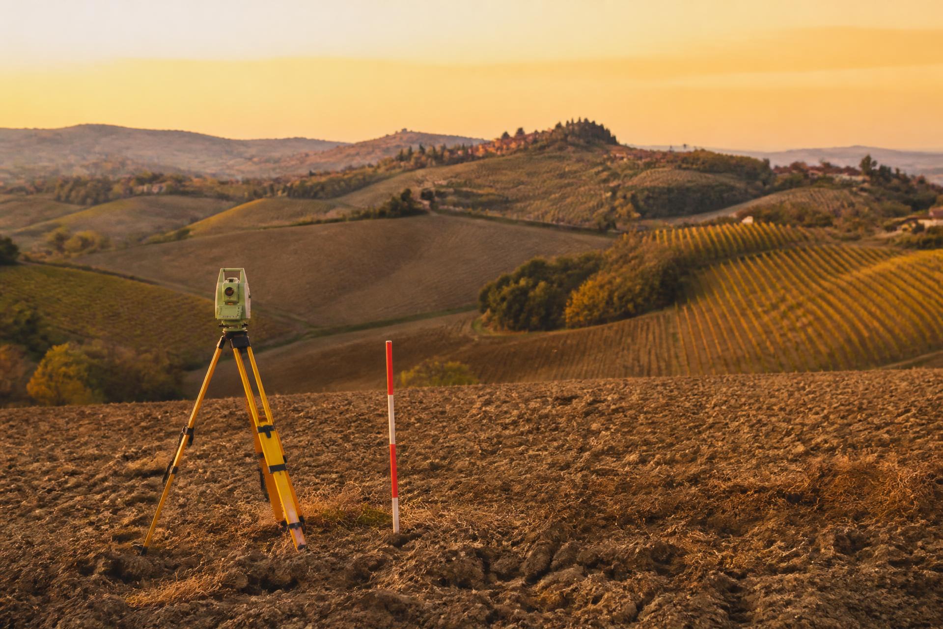 Strumentazione topografica su un campo arato nelle colline bolognesi